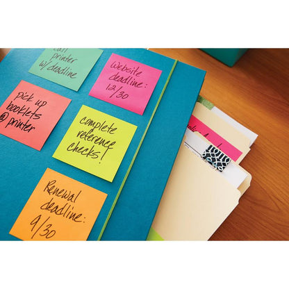 A blue folder with Post-it® notes from 3M Deutschland GmbH (76 mm x 76 mm, 100 sheets/block, 100% PEFC), on which tasks and appointments are noted, lies on a wooden table next to organized file folders with tabs.