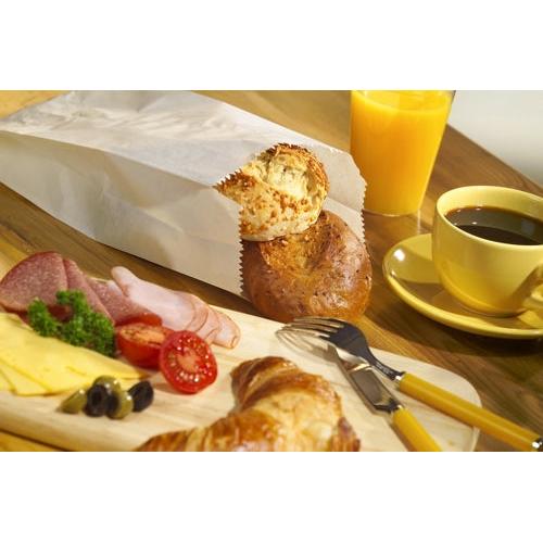 Ein Frühstücksaufstrich mit Käse, Salami, Schinken, Oliven und Tomaten auf einem Brett, ein Croissant, Kaffee, Orangensaft und zwei Brötchen in PAPSTAR 1000 Papierfaltenbeuteln aus Cellulose der PAPSTAR GmbH auf einem Holztisch.