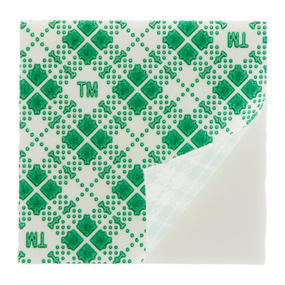 A square Scotch-FIX™ Double-Sided Indoor Mounting Square (25 mm x 25 mm) from 3M Germany GmbH with a green cross, dot, and "TM" pattern. One corner is folded to reveal the underside - ideal for stable indoor mounting. Pack of 16 pieces.