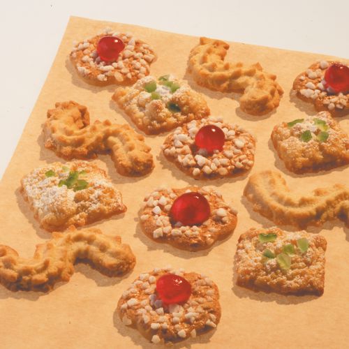 Twelve different butter cookies – some with nuts, red cherries, or green candied fruits – are arranged in rows on a sheet of PAPSTAR baking paper 38 cm wide from PAPSTAR GmbH with a practical non-stick surface.
