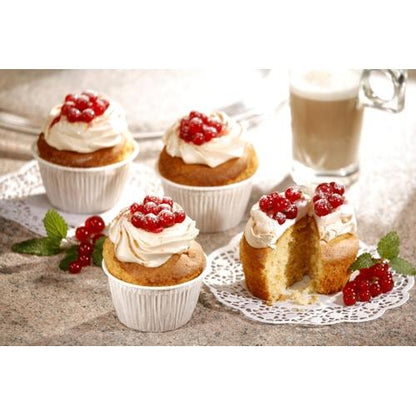 In PAPSTAR GmbH muffin baking cups Ø 5 cm, 3.5 cm high, white (20 pieces), four cupcakes with white icing and red berries sit on a countertop. One is cut open. In the background, a sprig of mint and a latte glass can be seen.