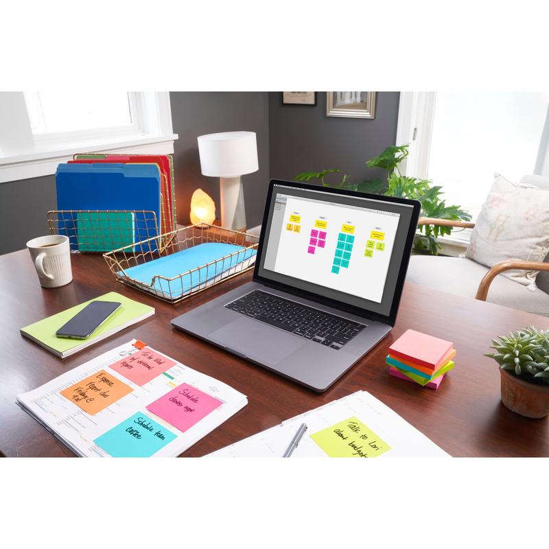 A desk with a laptop, on which a sticky note organizer, Post-it® Notes (76 mm x 76 mm, 100 sheets/block, 100% PEFC) from 3M Deutschland GmbH, binders, paperwork, a phone, a lamp, a plant, and sunlight illuminate the organized workspace.