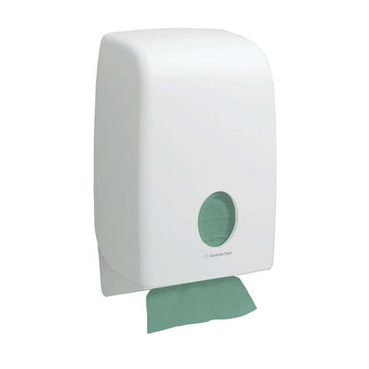 Ein weißer Wandspender mit kreisförmigem Fenster zeigt grüne Kimberly-Clark GmbH Hostess™ NATURA™ Zick-Zack-Faltung Handtücher (23 x 25 cm); ein umweltfreundliches Handtuch wird teilweise am unteren Rand gespendet.