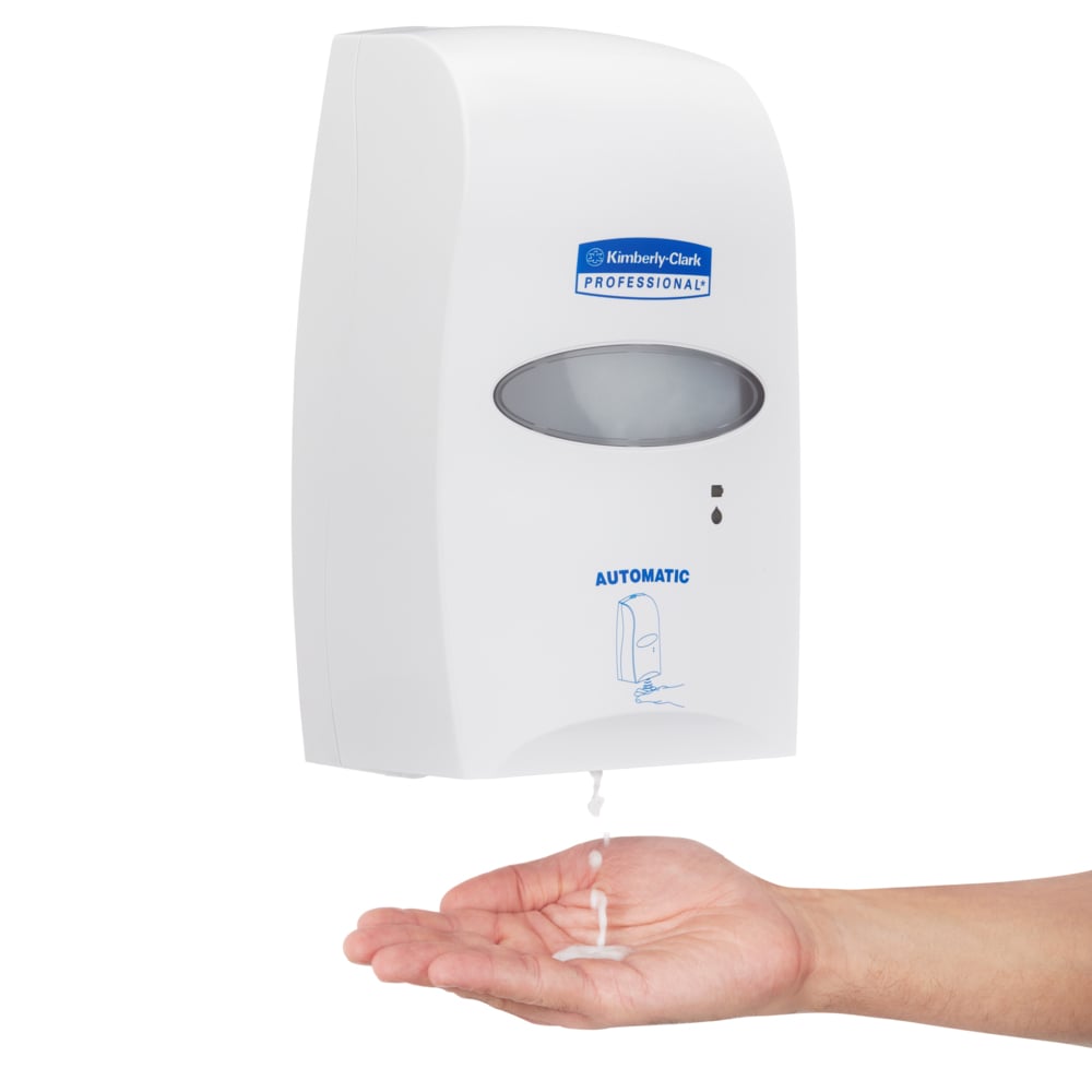 Eine Hand wird unter den Kimberly-Clark Professional™ Elektronischer Hautpflegespender (weiß, 1,2 Ltr) gehalten, der die Seife berührungslos auf die Handfläche abgibt. Das weiße Gerät hat ein Sichtfenster und trägt das Logo der Kimberly-Clark GmbH.