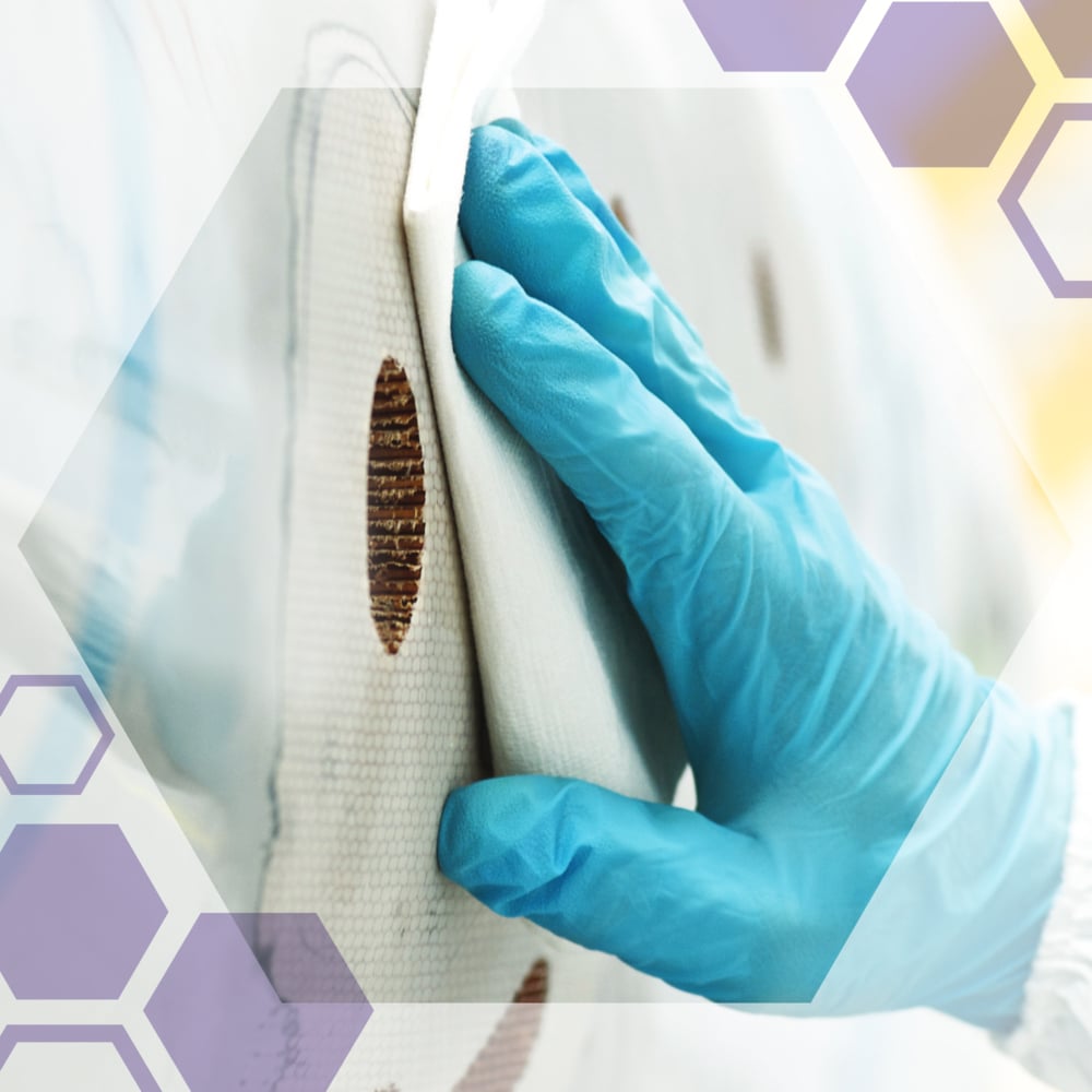 Eine behandschuhte Hand reinigt einen kreisförmigen braunen Fleck auf einer weißen Oberfläche mit Kimtech® Science Präzisionswischtüchern von Kimberly-Clark GmbH. Halbtransparente Sechsecke sind über das Bild gelegt.