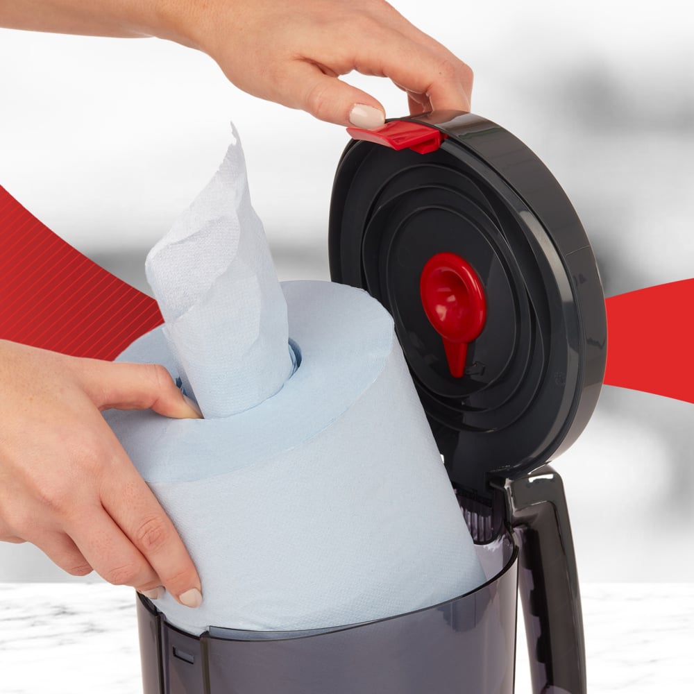 A user inserts a large blue roll into the open WypAll® Reach™ Centrefeed Dispenser (Black) from Kimberly-Clark GmbH, showing the red release mechanism - perfect for professional use.