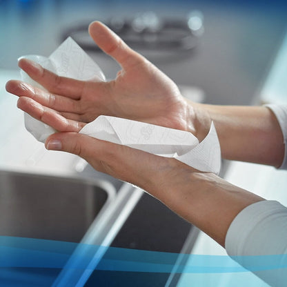 A person dries their hands with a Scott® Essential™ roll towel - E-roll Slimroll™ (White, 1-ply, 6x180m) from Kimberly-Clark GmbH over a kitchen sink - ideal for home or washrooms.