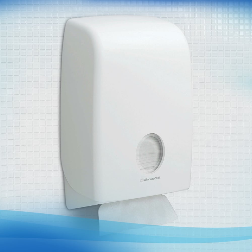 A white Scott® Control™ dispenser from Kimberly-Clark GmbH is mounted on a tiled wall. A sheet of flushable folded towels (white) is visible through the round window, showing the remaining supply inside.