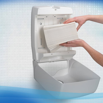 A person loads Scott® Control™ Flushable Folded Towels from Kimberly-Clark GmbH into an open wall dispenser in a white-tiled washroom, ensuring hygienic hand drying.