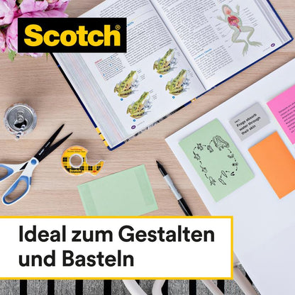 A workspace with colored sticky notes, scissors, ruler, beverage can, flowers, and an open biology book with frog illustrations is equipped with a roll of Scotch® double-sided tape, 12.7 mm x 7.89 m with dispenser from 3M Deutschland GmbH.