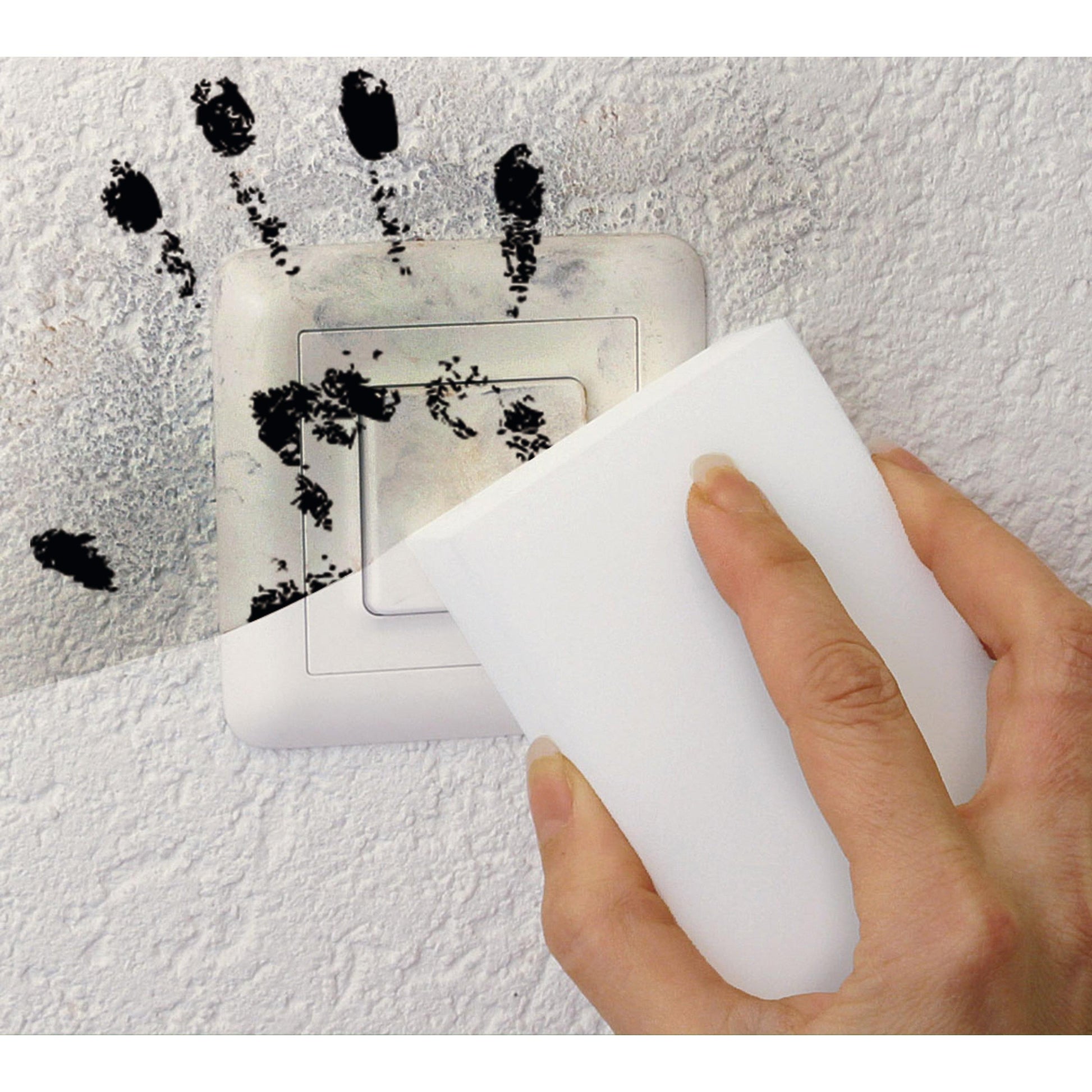Eine Hand wischt mit dem Scotch-Brite® Magic Pad der 3M Deutschland GmbH schwarze Handabdrücke von einem Lichtschalter auf einer strukturierten weißen Wand.