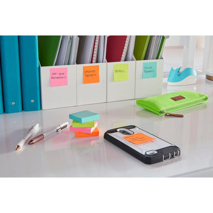 A tidy desk with a green pencil case, pens, 3M Post-it® Super Sticky Notes (47.6 x 47.6 mm, 90 sheets, 100% PEFC), a smartphone with a labeled note, folders for office supplies and reports, and a blue tape dispenser in the background.