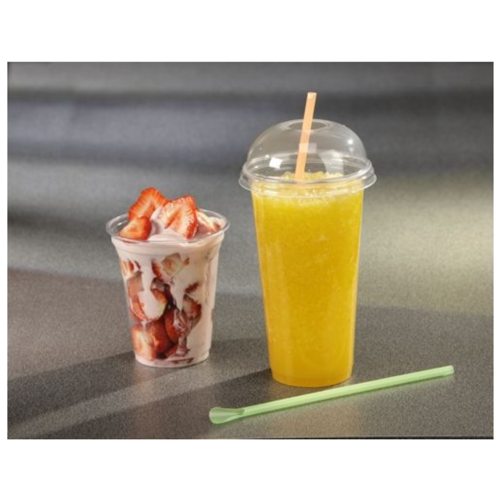 A Starpak plastic cup with sliced strawberries and whipped cream stands next to another Starpak plastic cup with a dome lid, containing a yellow smoothie. Next to it on the gray surface lies a light green straw.