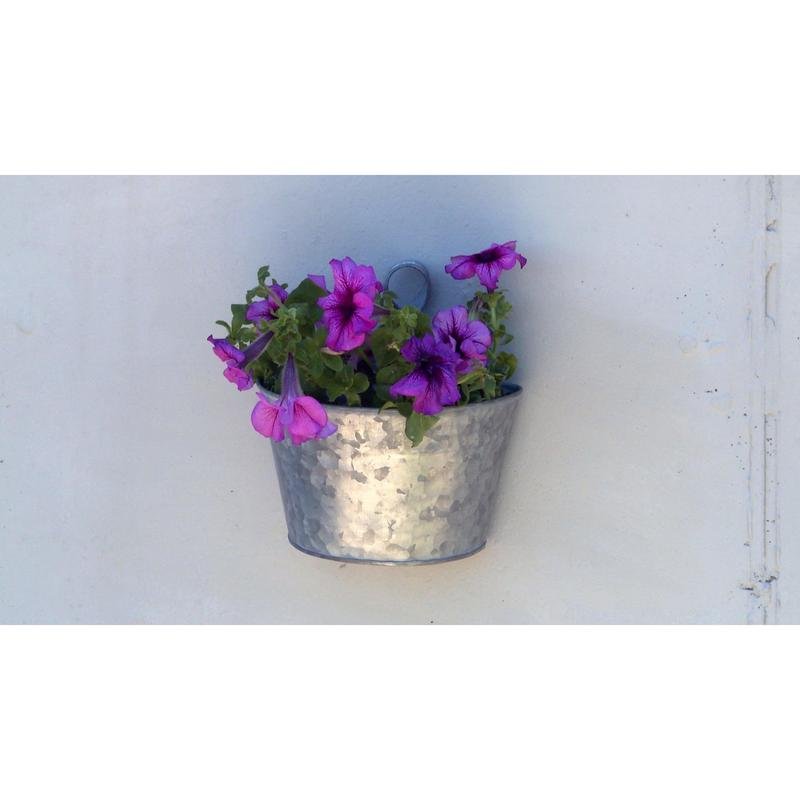 A metal pot with purple petunias and green leaves, mounted on a light wall with Scotch-FIX™ Extreme double-sided outdoor mounting tape from 3M Deutschland GmbH.
