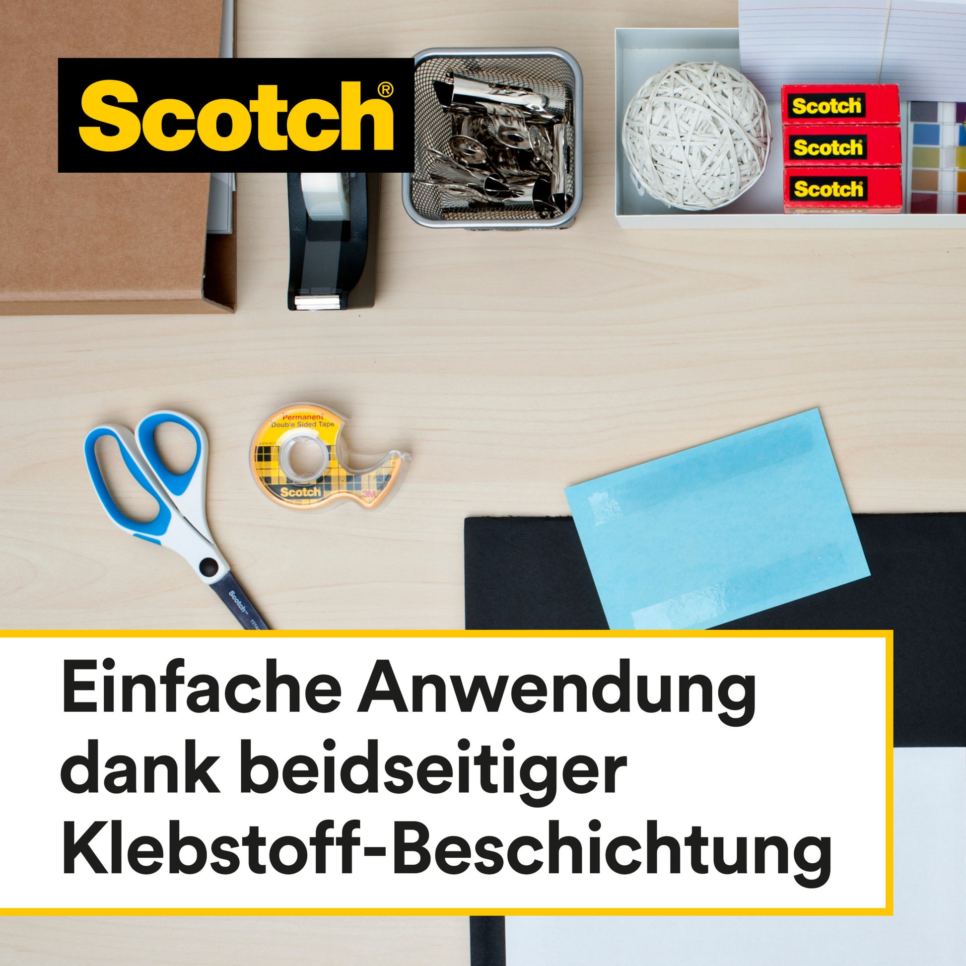 Scotch® doppelseitiges Klebeband (12,7 mm x 7,89 m, 25 % extra kostenlos) mit Handabroller von 3M Deutschland GmbH liegt zusammen mit Bürobedarf wie Schere, Heftgerät und Büroklammern auf einem hellen Holztisch.