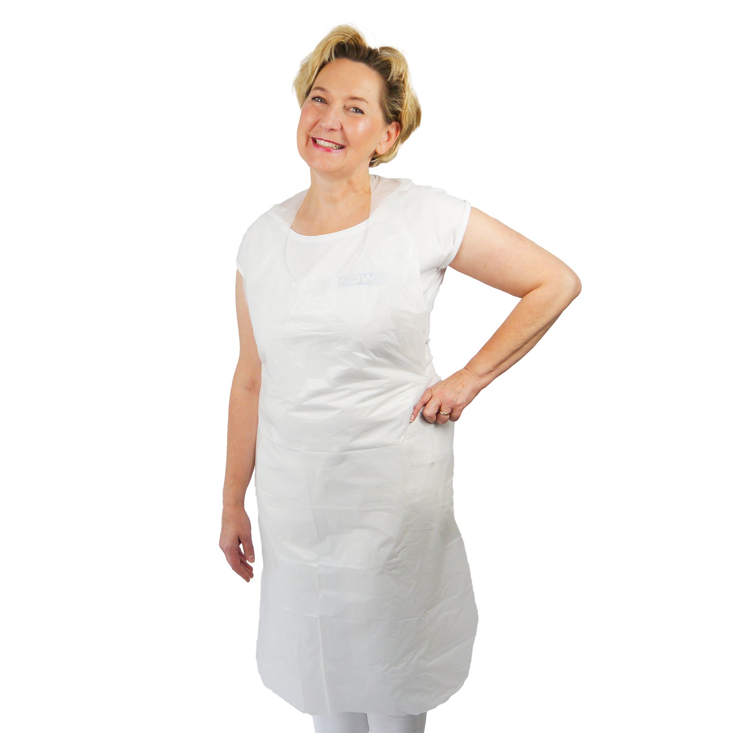A person is standing smiling with one hand on their hip, wearing the ARNOMED COVER PE-APRON Blocked Disposable Aprons made of PE by ARNOWA GmbH over a white shirt and pants against a plain white background.