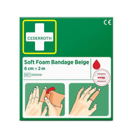 A green box labeled "Cederroth Soft Foam Bandage, Beige, 6 cm x 2 m | Package (1 piece)" by Orkla Wound Care AB features a white cross logo, the product code 51011019, and two illustrated instructions for applying the beige bandage to a hand.