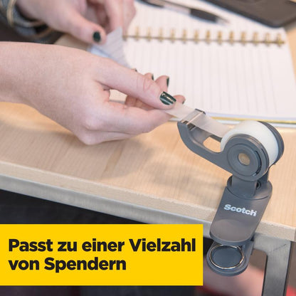 A person pulls a strip of Scotch® Magic™ Invisible Tape, Value Pack 14 rolls, 19 mm x 33 m (3M Deutschland GmbH) from a dispenser on a wooden table, with an open spiral-bound notebook in the background.