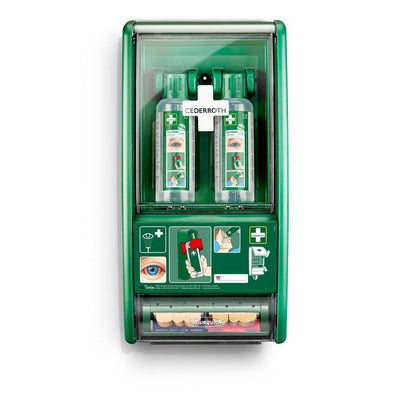 A green Cederroth eye wash station from Orkla Wound Care AB is mounted on the wall and contains 2 x 500 ml bottles (725200) as well as a Salvequick plaster dispenser (490700) with illustrated emergency instructions and symbols.