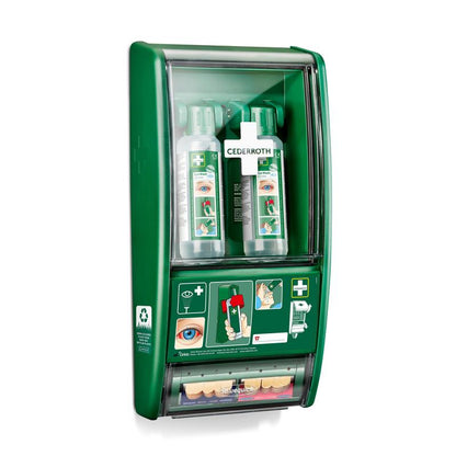 The Orkla Wound Care AB Cederroth eye wash station consists of two 500 ml bottles (725200) and a Salvequick plaster dispenser (490700), all secured behind a transparent cover on the wall, where the instructions for use and the brand name are visible.