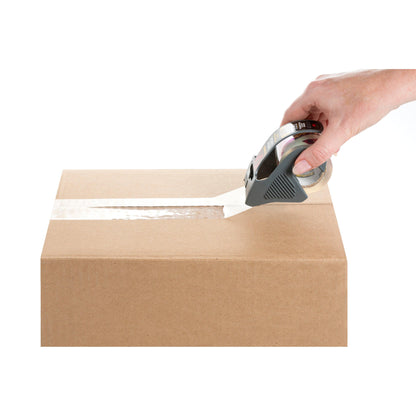 Eine Hand verschließt einen braunen Karton über die obere Naht mit Scotch® Box Lock™ Verpackungsklebeband 48 mm x 20,3 m von 3M Deutschland GmbH mit einem Klebebandabroller, alles vor einem weißen Hintergrund.