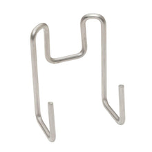 The TASKI accessory hook from Diversey Deutschland GmbH & Co. OHG is a metal wire hook with two prongs and a curved tip, ideal for storing cleaning accessories. It stands upright on a white surface.