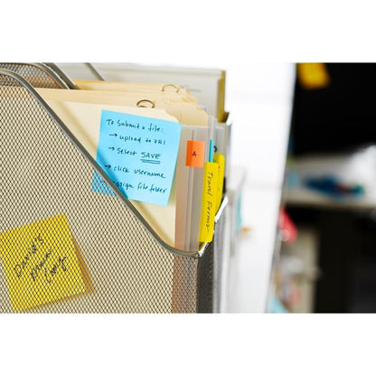 A wire mesh folder holds manila folders with colored tabs and handwritten labels. A blue Post-it® Notes cube (76x76 mm, 450 sheets/block, 100% PEFC) from 3M Deutschland GmbH is attached; more sticky notes appear in the background.