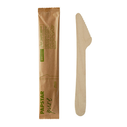 Pictured is a PAPSTAR wooden knife "pure" 16.5 cm and the corresponding labeled packaging paper | shrink wrap individually packaged (50 pieces) by PAPSTAR GmbH on a white background. The packaging is provided with green and black lettering.