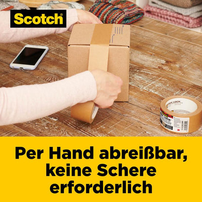 A person tears Scotch® Box Lock™ Paper Packaging Tape by hand to seal a box on a wooden table. Visible are a roll of tape, a smartphone, and folded textiles. The German text highlights the easy-tear feature of 3M Deutschland GmbH.