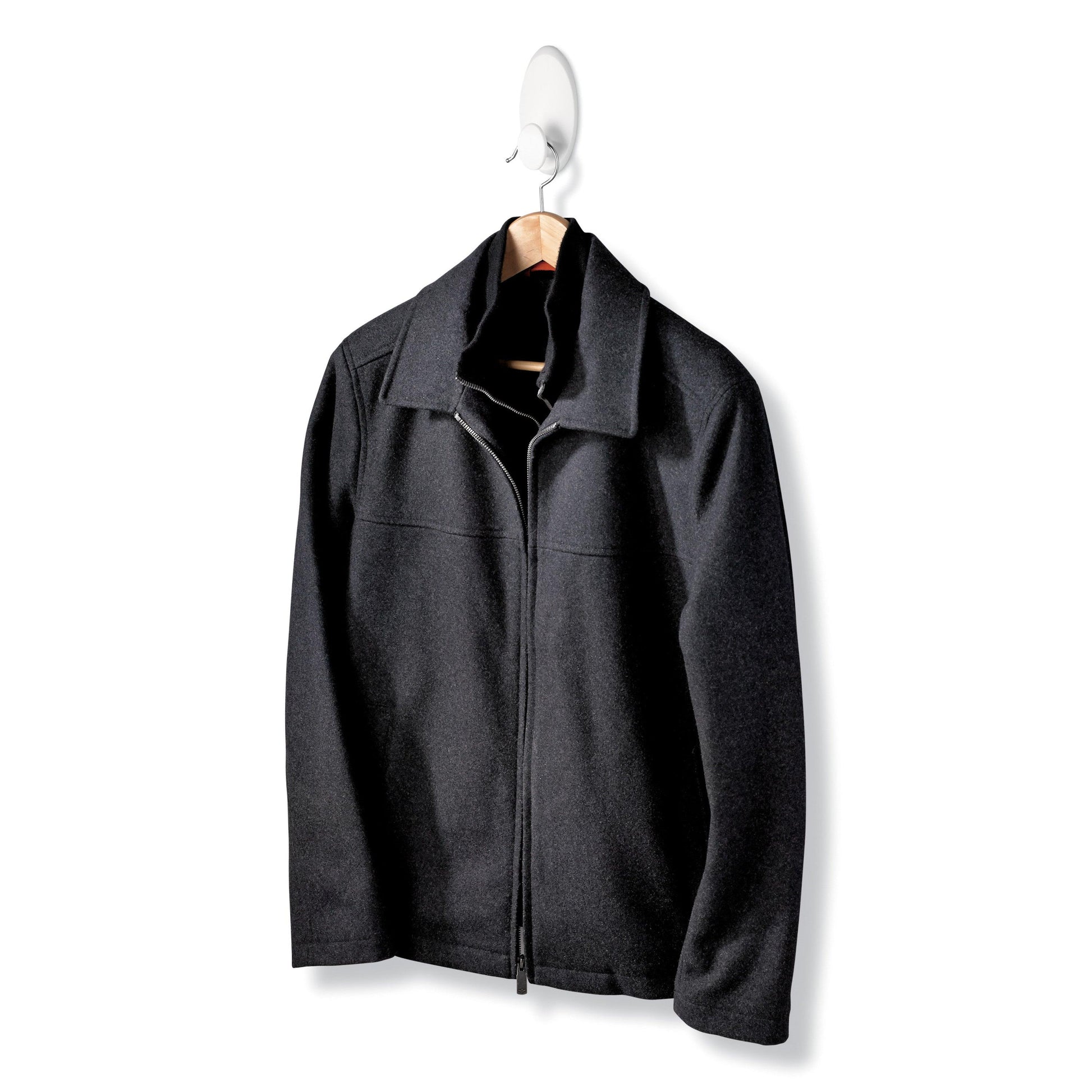 Eine schwarze Jacke mit Reißverschluss und Kragen hängt an einem Holzbügel, der auf einem Command™ Kleider-Haken, 17019-FGN (1 Stück) von 3M Deutschland GmbH vor weißem Hintergrund angebracht ist.