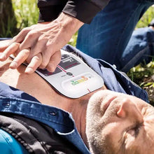 Ein erwachsener Mann erhält eine Herzdruckmassage mit dem innotas Beurer LifePad® Reanimationshilfe (Auslaufartikel, 1 Stück), während ein AED-Pad an seiner nackten Brust für eine effektive Erste Hilfe angebracht ist.