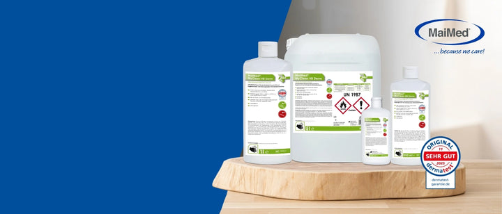 MaiMed Desinfektionsprodukte in verschiedenen Größen (Flaschen und Kanister) stehen auf einer Holzplatte vor neutralem Hintergrund. Links ist eine blaue Fläche, rechts oben das MaiMed-Logo mit dem Slogan „because we care!“. Unten rechts ist ein Dermatest-Siegel „SEHR GUT 2025“ zu sehen.