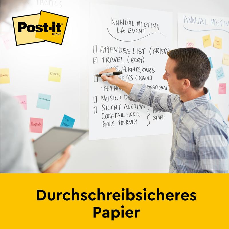Ein Mann schreibt auf eine 3M Post-it® Super Sticky Meeting Chart (63,5 x 76,2 cm, selbsthaftend, 30 Blatt/Block), die an der Wand befestigt ist, während ein anderer ein Tablet hält. Die weiße Karte zeigt Notizen für eine Veranstaltung. Text: "Durchschreibsicheres Papier.
