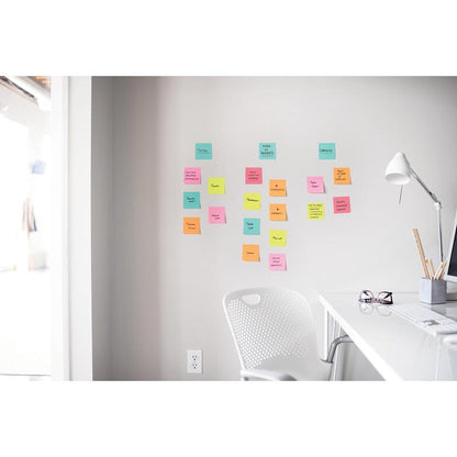 A white desk with a lamp, pen holder, and glasses stands next to a white chair. Above, in a bright office, Post-it® Super Sticky Notes (47.6 mm x 47.6 mm, 90 sheets/block, 100% PEFC) from 3M Deutschland GmbH are attached to the wall.
