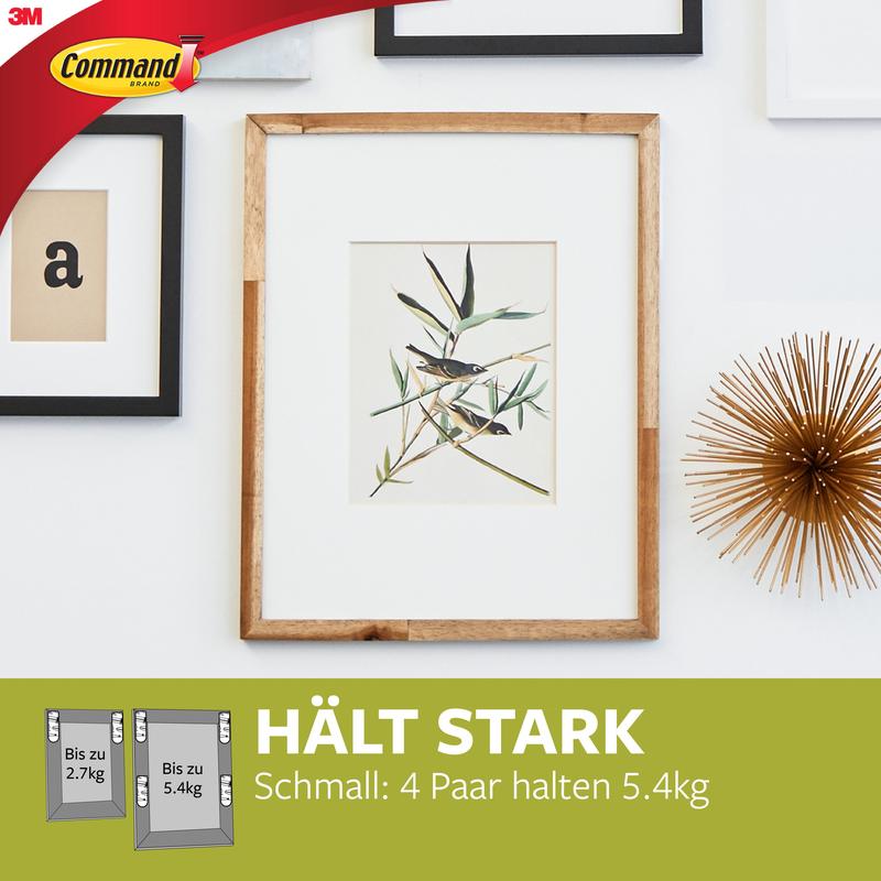 Ein gerahmter Pflanzendruck hängt an einer weißen Wand mit anderen Rahmen und einem Goldobjekt. Unten werden die Schmale Command™ Bilder-Montage Strips (M) 17207 der 3M Deutschland GmbH wegen ihrer rückstandslos entfernbaren und starken Haltekraft beworben.