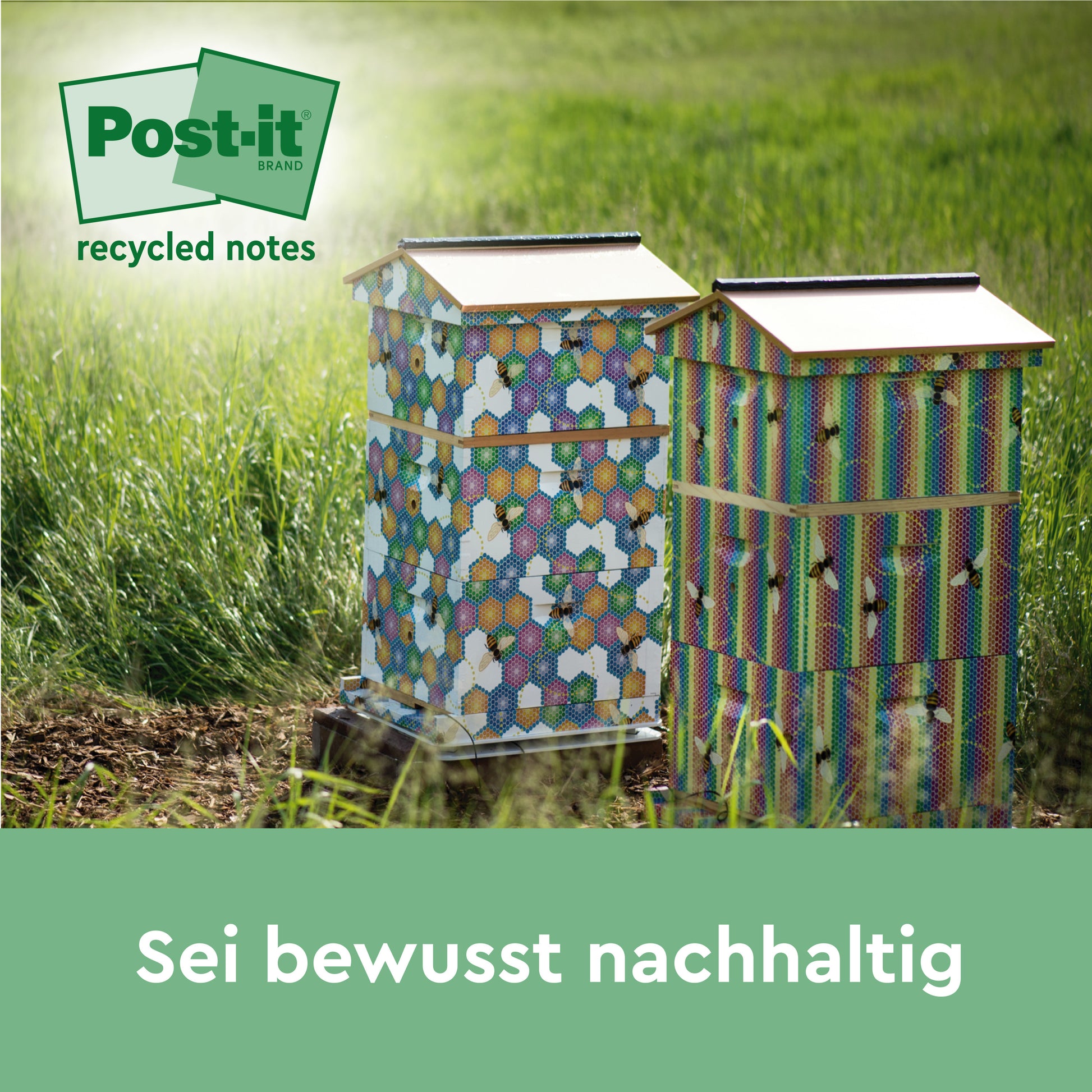 Zwei bunte Bienenstöcke stehen auf einer Wiese im Sonnenlicht. Das Logo von Post-it® Super Sticky 100% Recycling Notes (3M Deutschland GmbH) befindet sich oben links. Unten steht der Text "Sei bewusst nachhaltig" in deutscher Sprache.