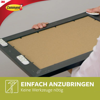 Eine Person klebt Schmale Command™ Bilder-Montage Strips (M) 17207 von 3M Deutschland GmbH auf einen rechteckigen Rahmen. Text: "EINFACH ANZUBRINGEN Keine Werkzeuge nötig." Das 3M Command Logo hebt die schmale Bilderbefestigung hervor.