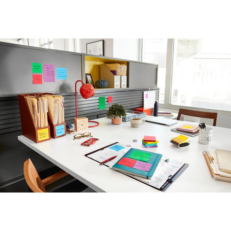 A tidy office with Post-it® Super Sticky Notes (47.6 mm x 47.6 mm, 90 sheets/block, 100% PEFC) from 3M Deutschland GmbH, folders, notebooks, a red lamp, a potted plant, and other utensils, organized on a white desk and gray shelves.