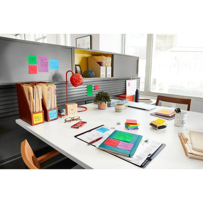 A tidy office with Post-it® Super Sticky Notes (47.6 mm x 47.6 mm, 90 sheets/block, 100% PEFC) from 3M Deutschland GmbH, folders, notebooks, a red lamp, a potted plant, and other utensils, organized on a white desk and gray shelves.