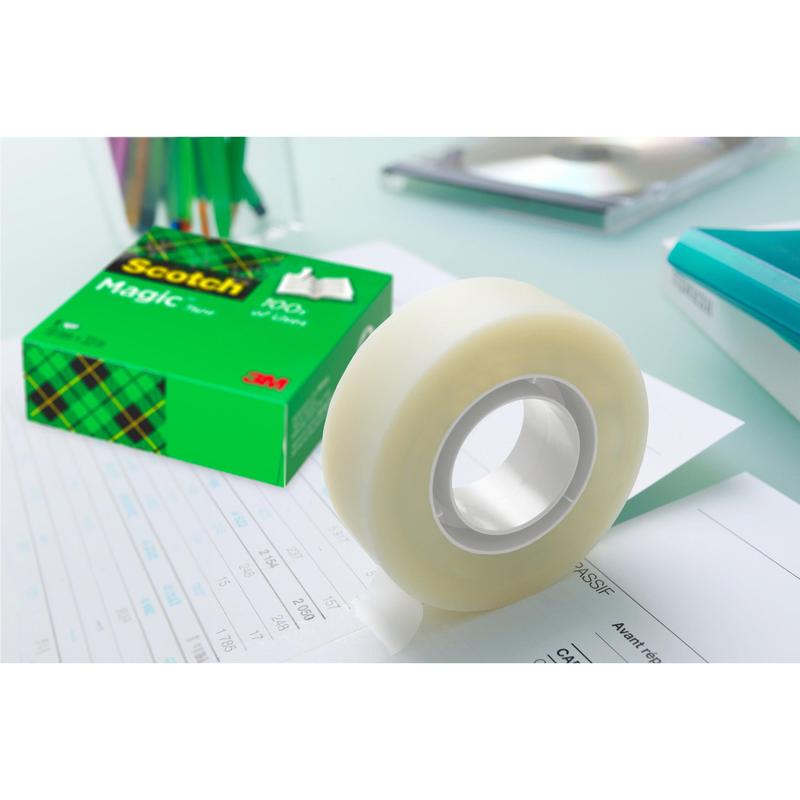 A roll of Scotch® Magic™ Invisible Tape from 3M Deutschland GmbH lies in the green box on the paper - ideal for any desk, especially in the value pack with 14 rolls (19 mm x 33 m).