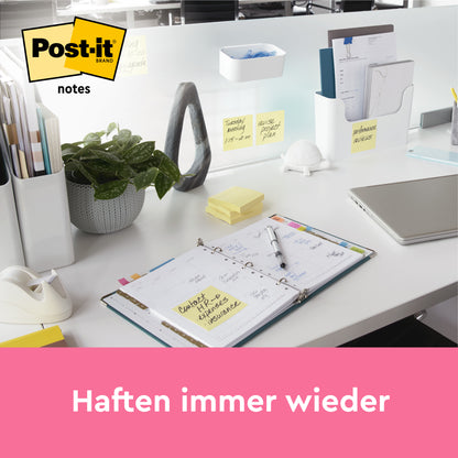 Ein Schreibtisch mit Büromaterialien, einem offenen Planer, Ordnern, Pflanzen und mehreren Post-it® Super Sticky Z-Notes (76x127 mm, 100 Blatt/Block, Kartonverpackung, 100% PEFC) der 3M Deutschland GmbH auf dem Schreibtisch und der Trennwand. "Haften immer wieder.